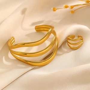 Vue détaillée de l'ensemble bracelet manchette doré à vagues et bague ouverte sur soie