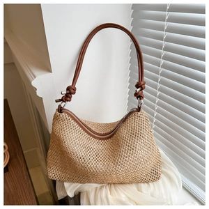 Close-up of straw beach bag featuring brown leather knot strap and woven texture detail
