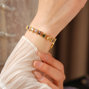 Detail of 18K gold plated bracelet featuring multi-colored heart gemstones on a wrist