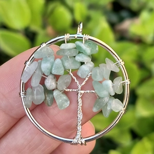Close-up of handmade Tree of Life pendant with silver wire and green gemstones