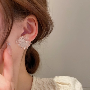Close-up of translucent resin flower earring worn on ear showing delicate petals