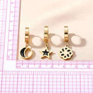 Three pairs of gold stainless steel hoop earrings with star and moon charms on white fabric