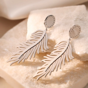 Silver hollow feather drop earrings in titanium steel on a neutral stone display