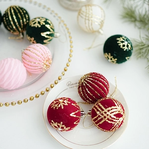 Close-up of velvet Christmas ornaments with gold glitter snowflake and stripe patterns