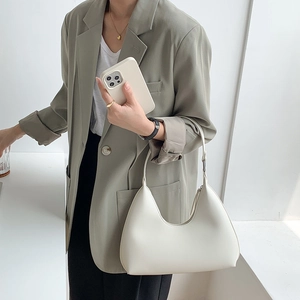 Chic cream white crescent underarm bag in premium PU leather held by a model in a suit