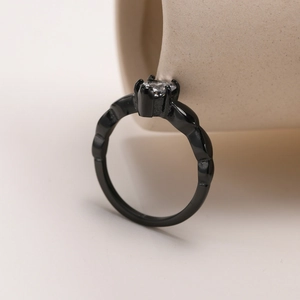 Detailed close-up of a black twisted band ring with a sparkling clear zircon stone