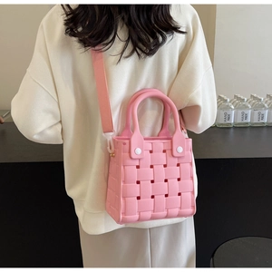 Pink EVA woven texture beach bag worn by a model in a minimalist indoor setting