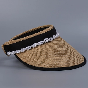 Detail of wide-brim straw sun hat featuring elegant double-row pearl trim on the headband