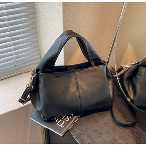 Detail of black pebbled leather crossbody bag with adjustable strap in a lifestyle setting