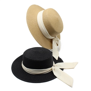 Detail of woven straw hats featuring elegant cream ribbons with rhinestone buckles