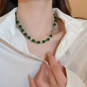 Détail d'un collier de perles en verre vert émeraude avec des perles de séparation