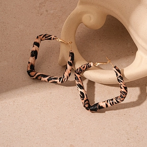 Detail of square leopard print earrings with gold metal hoops on minimalist stone stand
