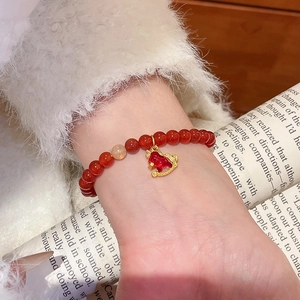 Gros plan d'un bracelet en agate rouge avec un pendentif poney doré au poignet