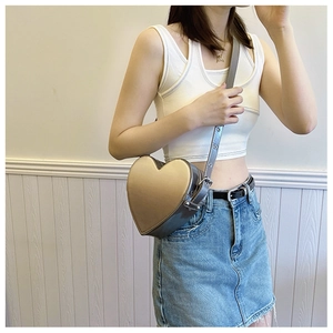 Détail d'un sac bandoulière en forme de cœur doré champagne avec bandoulière réglable