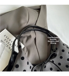 Close-up of gray canvas tote with black polka dots and shiny black handles and bow