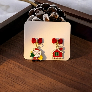 Détail de boucles d'oreilles de Noël asymétriques avec Père Noël et maison rouge sur bois