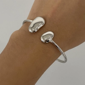 Vue macro d'un bracelet jonc ouvert argenté avec un design double goutte minimaliste