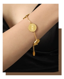Detail of a gold plated titanium steel bracelet with sunburst textured round charms
