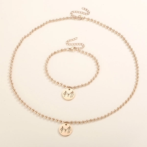 Detail of gold bead chain jewelry set featuring a circular family silhouette pendant