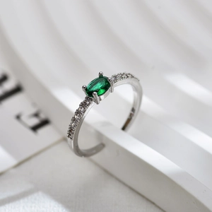 Macro shot of oval green gemstone ring with pavé diamonds on a white geometric stand