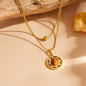 Détail d'une double chaîne serpent avec pendentif soleil et pierre œil de chat brune