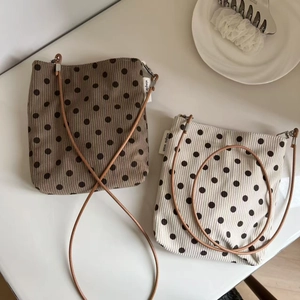 Close-up of corduroy polka dot crossbody bags in brown and beige with simple wish labels