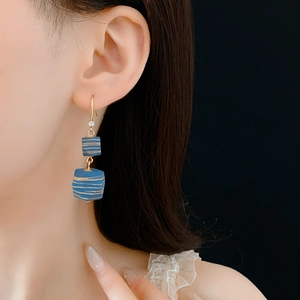 Detail of vintage geometric earrings with blue and gold wooden beads and zircon accents