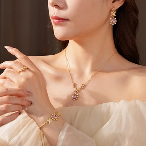 Detail of vintage style jewelry set featuring pink oval stones and gold finish on model