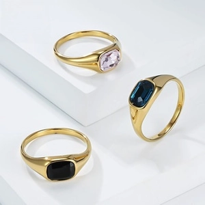 Primer plano de anillos de tungsteno dorado con incrustaciones de gemas de colores