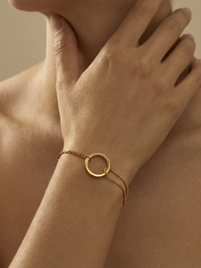 Detailed close-up of a dual-layer gold chain bracelet with a polished ring element