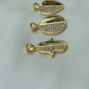 Macro shot of gold-plated Hamsa, heart, and oval pendants with white cubic zirconia