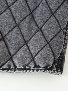 Detailed macro view of diamond quilted washed denim fabric with deep grey cotton padding