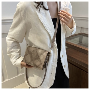 Close-up of khaki geometric quilted crossbody bag styled with a white textured blazer