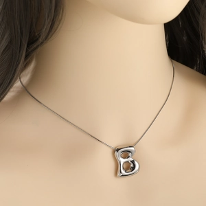 Polished silver capital letter B pendant necklace on model's neck for a minimalist look