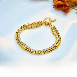 Detail of gold double-layer chain bracelet featuring rhinestone link and bead design
