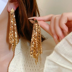Close-up of golden geometric mesh tassel earrings with shimmering metal scale detail