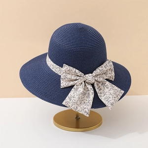 Chapeau de soleil en paille bleu marine avec ruban floral sur un support doré chic