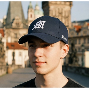 Close-up of embroidered gothic MH letters on a navy blue cotton baseball cap