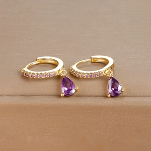 Elegant gold drop earrings with purple pear-cut crystals and pavé stones on a display box