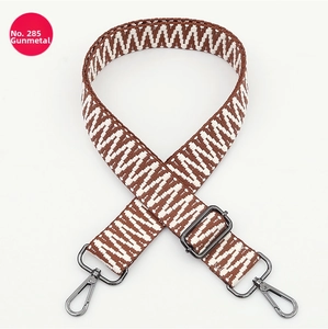 Detail of adjustable geometric woven bag strap with gunmetal hardware and lobster clasps