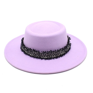 Detalle de un sombrero boater de lana lavanda con una banda decorativa negra