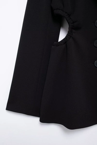Detailed close-up of side cutout with elastic ruching on a black long sleeve blazer