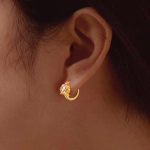 Close-up of golden crown earrings featuring heart-shaped stones on elegant model