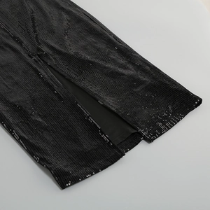 Detail shot of the sequin fabric texture and side slit hem on this black party dress