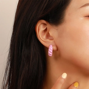 Detail of pink twisted hoop earring with textured alloy finish on a model's ear