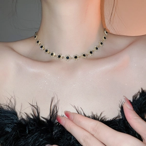 Close-up of sparkling floral pendant necklace with black stones and diamond accents