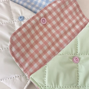 Close-up of quilted fabric sanitary pouch with snap button in various pastel colors