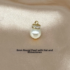 Detail of 8mm round pearl pendant with gold diamond-set cap on champagne silk fabric