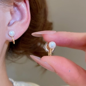 Close-up of pearl ear clip with gold metal finish and transparent silicone comfort pad