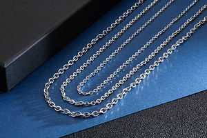Three assorted silver stainless steel O-chains arranged on a premium blue background